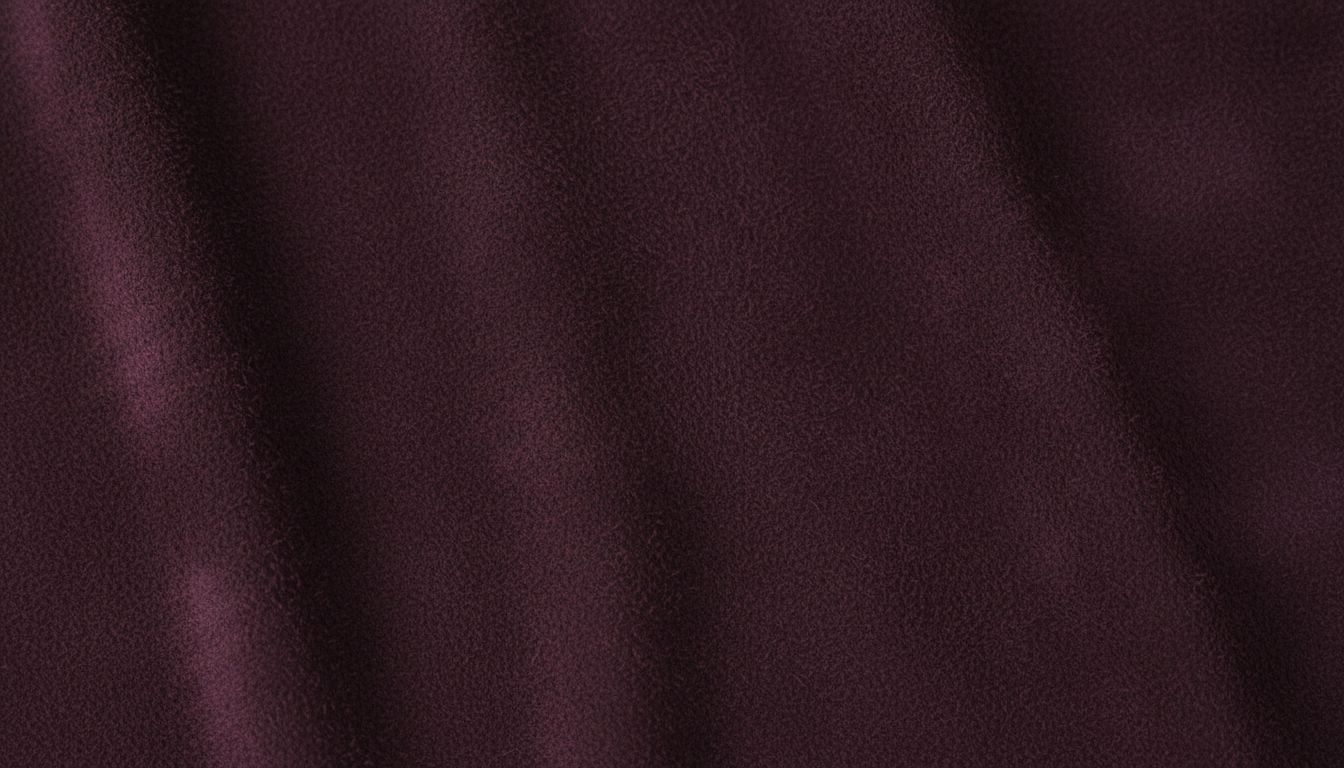 Крупный план текстуры плотной замши оттенка баклажана, показывающий матовую, глубокую поверхность.